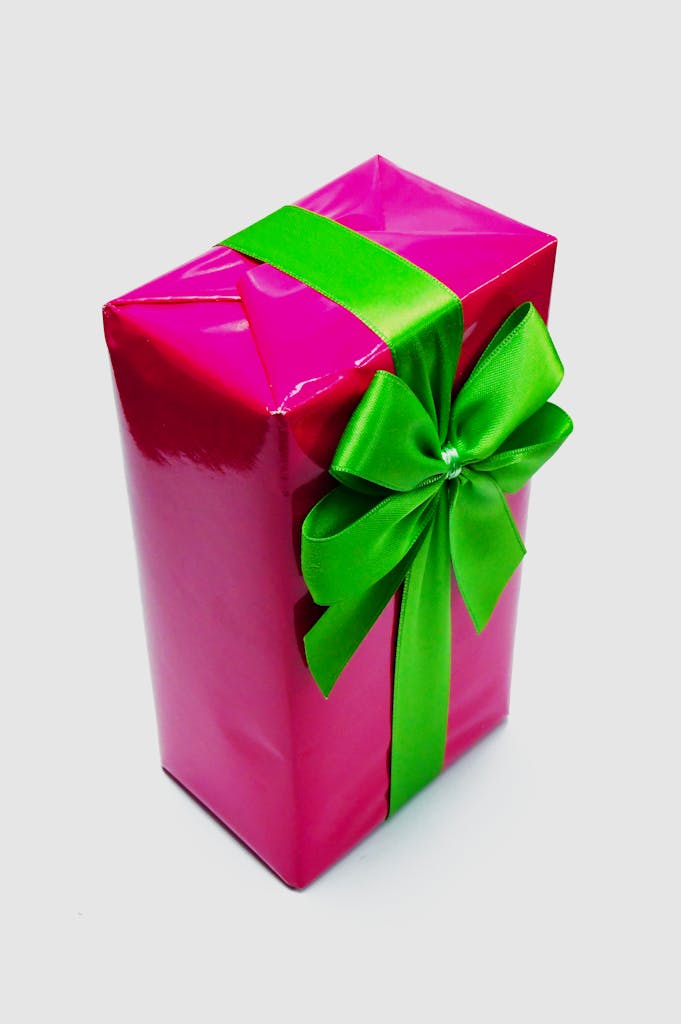 A brightly wrapped pink gift box with a decorative green ribbon.